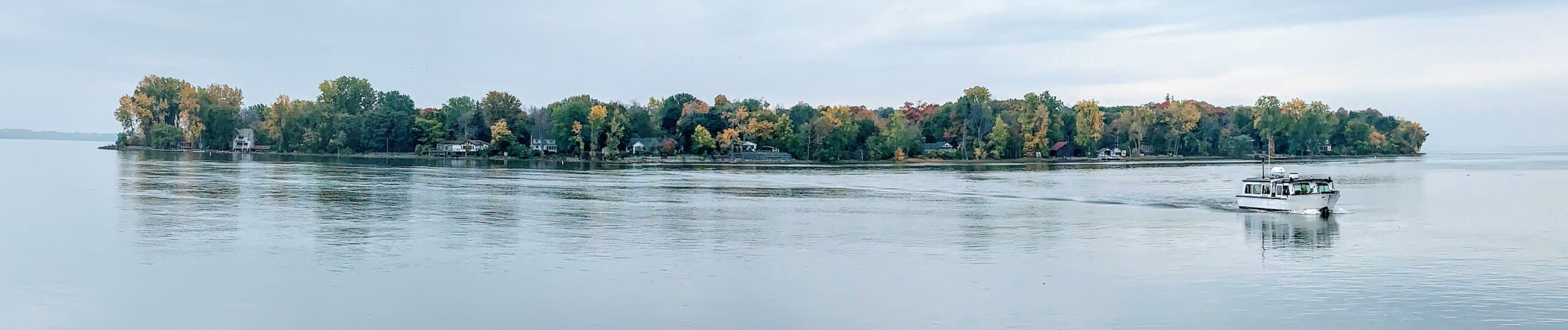 Vue panoramique de L'Île-Dorval dans le fleuve Saint-Laurent, avec le traversier qui approche du rivage.